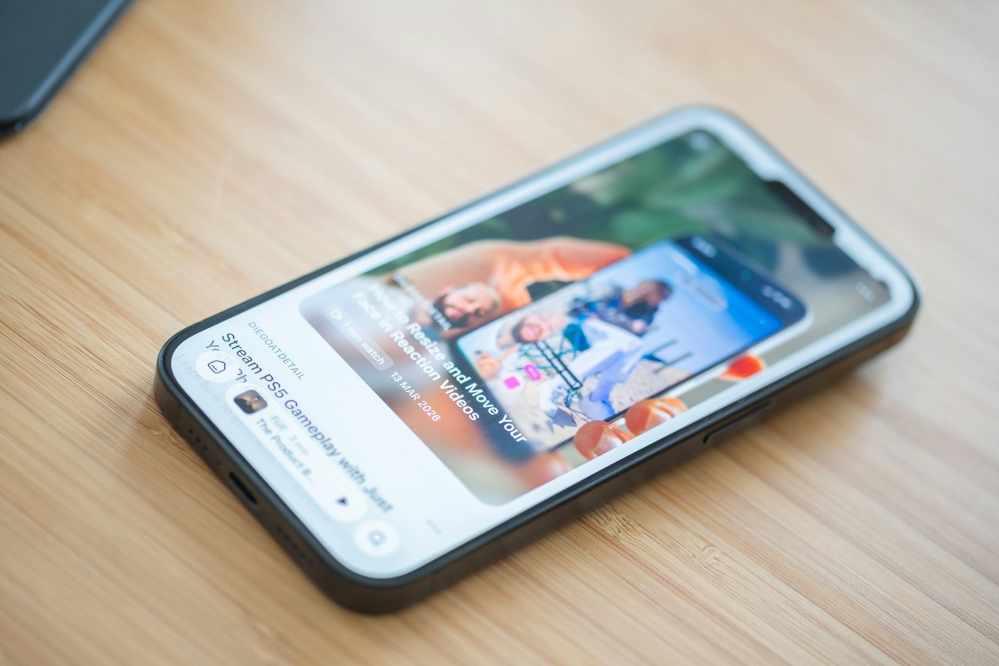 Smartphone-Bildschirm mit einem Video-Tutorial auf einer Holzoberfläche.